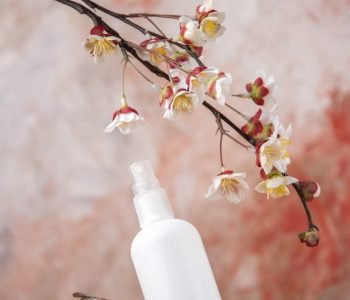 front-view-empty-spray-bottle-tree-branch-flower-branch-nude-background_140725-112270